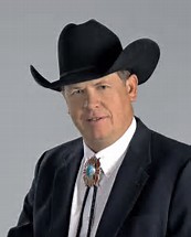 Aubrey Dunn headshot dark suit, white shirt, bolo tie, black cowboy hat (color photo)