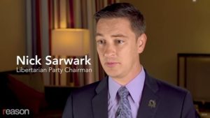 TV screen image with Reason logo and Nicholas Sarwark indoors wearing suit and tie on camera speaking, text reads 'Nick Sarwark Libertarian Party Chairman'