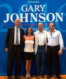 Photo of four people posing, standing in front of a 'Gary Johnson 2016' blue backdrop- from left to right areBill Weld, Abigail DuBearn, Gary Johnson, Sacha DuBearn (color photo)